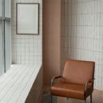 Brązowy fotel przy oknie i drewnianej ramie w jasnym salonie